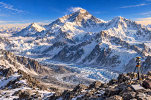 Mount Everest towers above Himalayan peaks and glaciers, with a surveyor's tripod in the foreground.