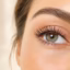Close-up of a woman's eye with naturally lifted, curled eyelashes and soft, natural makeup.