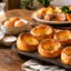 Golden Yorkshire puddings in a baking tray beside flour, eggs, milk, and a traditional Sunday roast with vegetables.
